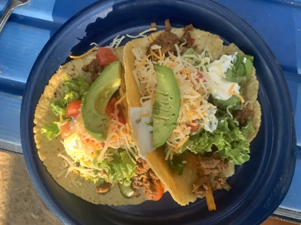 Three hard-shell tacos on dark blue plate and ground meat filling in Grand Teton National Park.