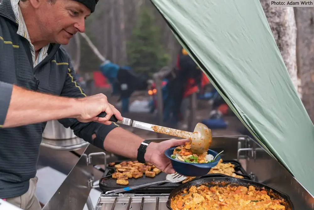 Campfire with flames and cooking pot or kettle over fire in Grand Teton National Park.