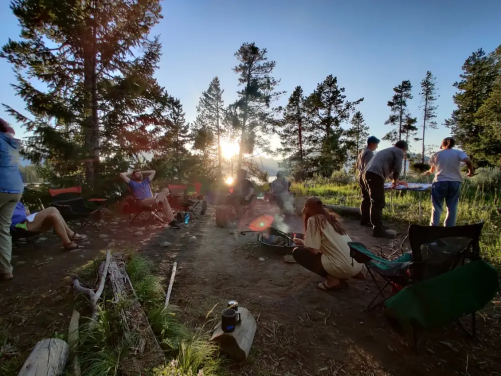 Kayaker in yellow or lime green kayak and person wearing red or orange life jacket in Grand Teton National Park.