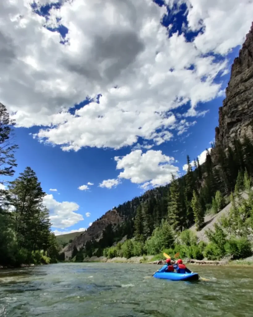 Person in yellow kayak and river with white water rapids in Grand Teton National Park.