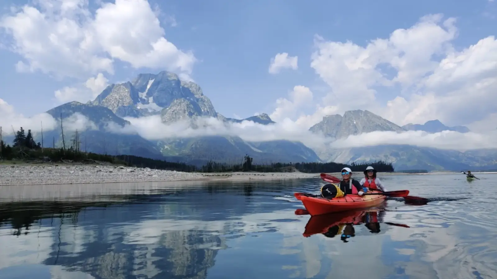 Person in yellow kayak and calm river water in Grand Teton National Park.