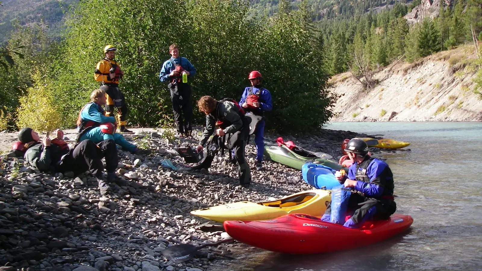 Rocky riverbank with rounded stones and shallow river water at right edge in Jackson Hole.