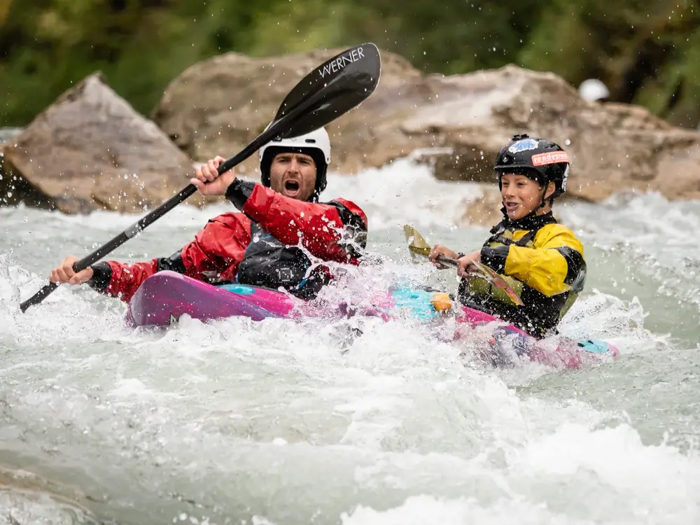 Two people in a tandem kayak and both wearing helmets in Jackson Hole.