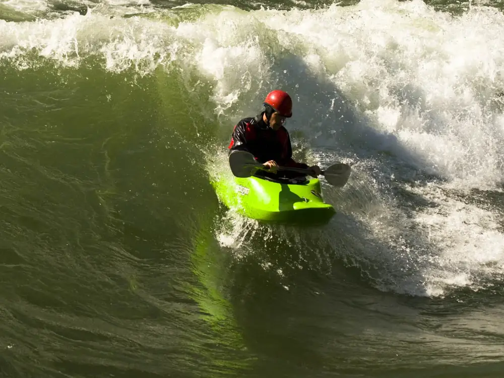 Single person in red kayak and calm river or lake water in Jackson Hole.