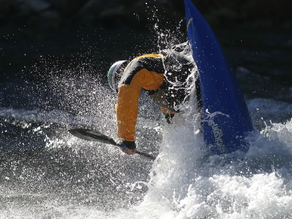 One person in a blue kayak and person wearing a helmet in Jackson Hole.