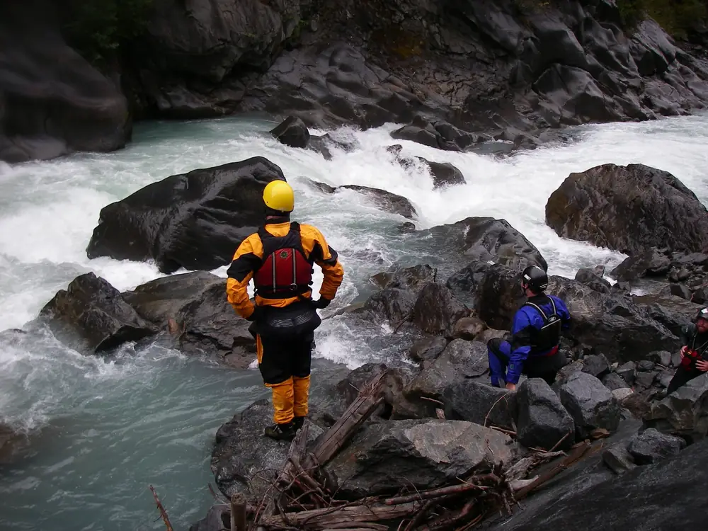 Fast-moving river with whitewater and large dark rock formations in the river in Jackson Hole.