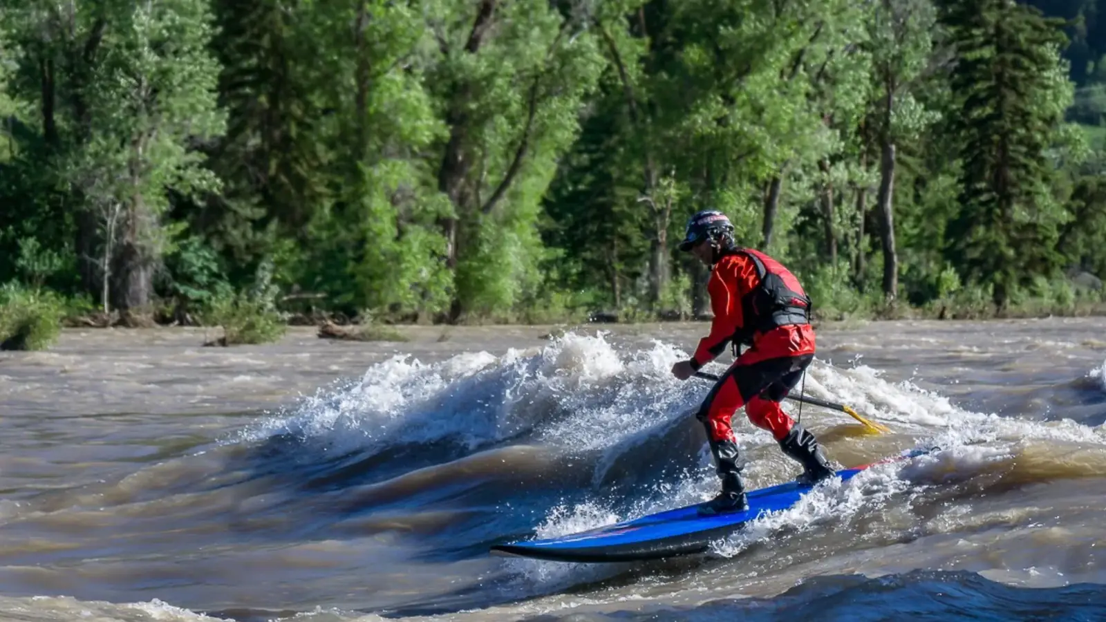One person standing on a blue board and yellow paddle in the person's hands in Jackson Hole.