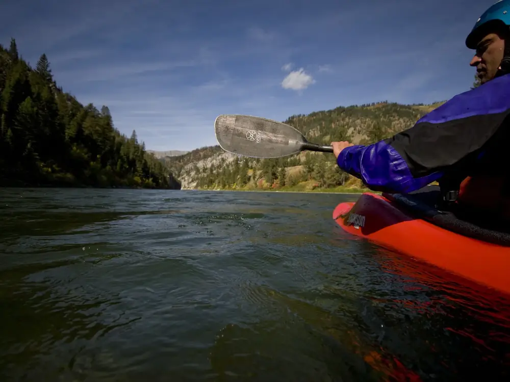 One person in a red kayak and blue helmet in Yellowstone National Park.