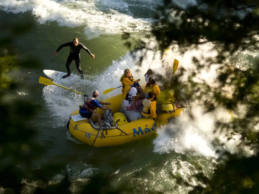 Person in yellow kayak on calm water and wooden dock or pier structure on right side in Yellowstone National Park.