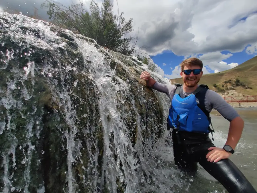 Single person in red kayak and calm river water in Jackson Hole.