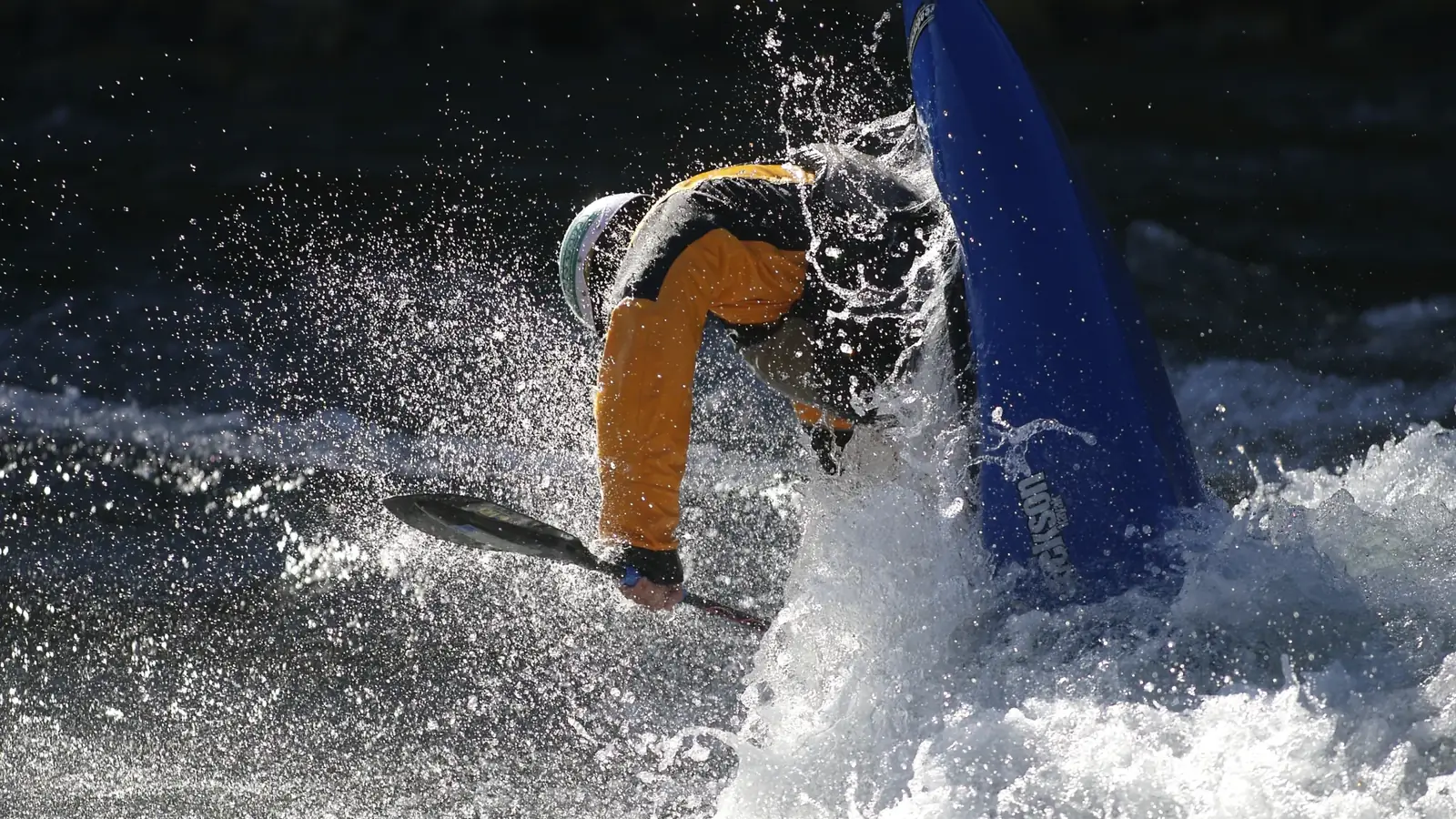 One person in a blue kayak and person wearing a helmet in Jackson Hole.