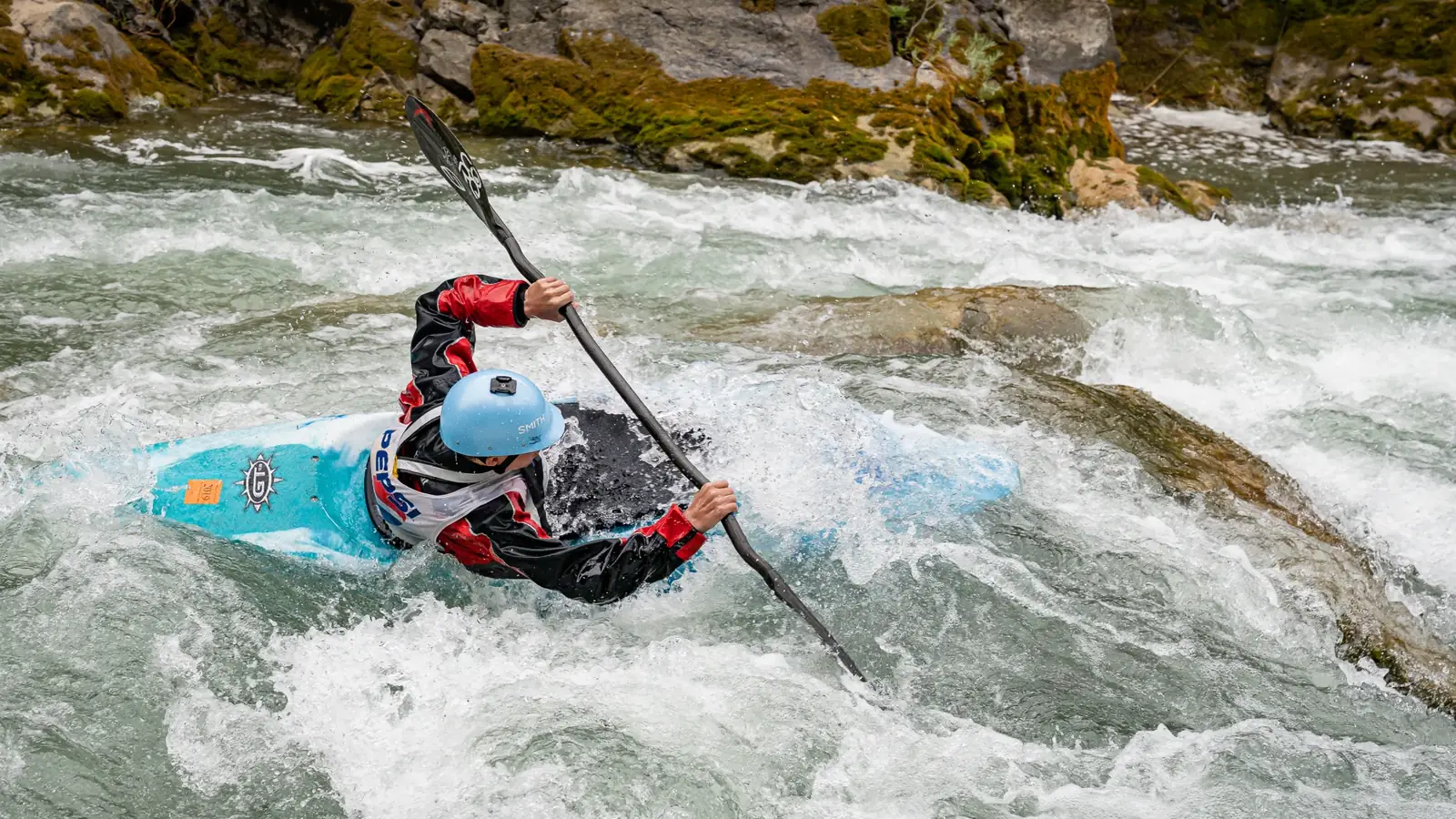 One person in a blue kayak and whitewater rapids with splashing water in Jackson Hole.