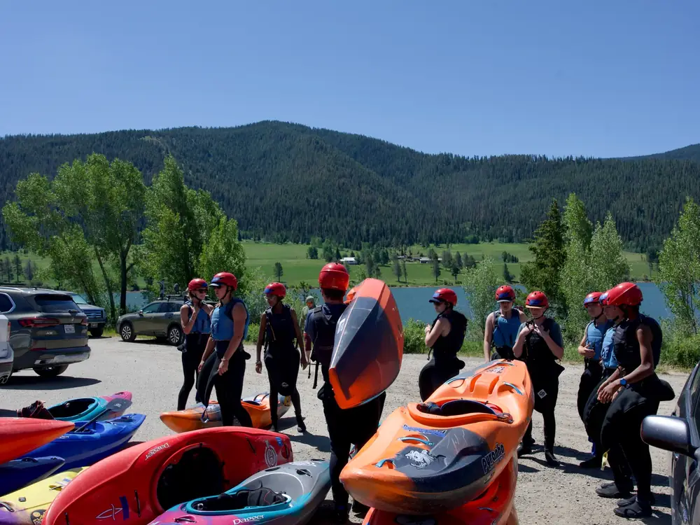 Eight people standing on a gravel lot and most people wearing red helmets in Jackson Hole.
