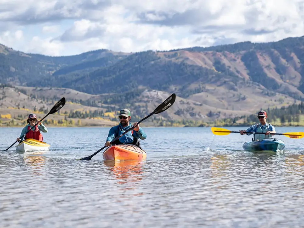 Single person in red kayak and calm lake with reflections in Jackson Hole.