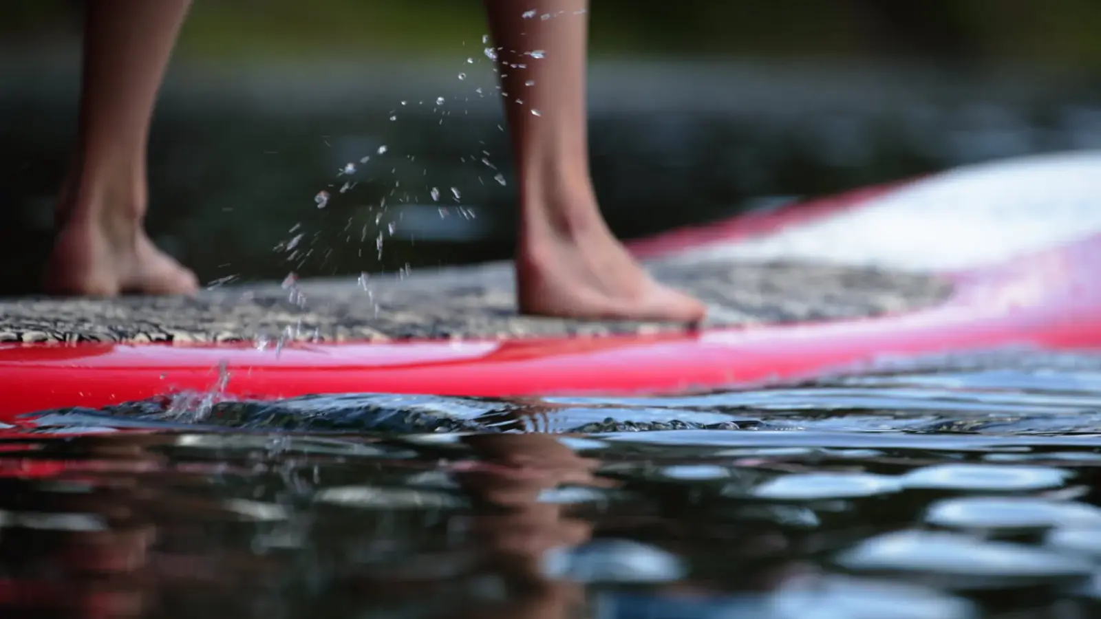 Bare feet and lower legs and red board with textured deck pad in Slide Lake.