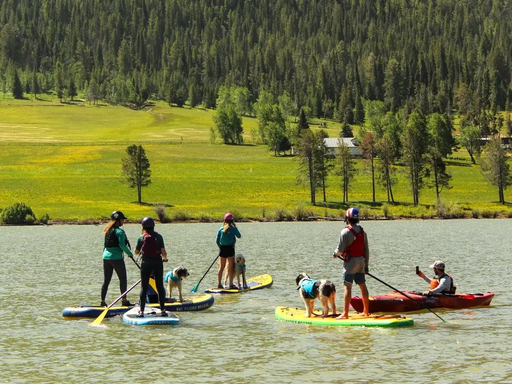 Calm lake or pond with light brown water and seven people on water in Slide Lake.
