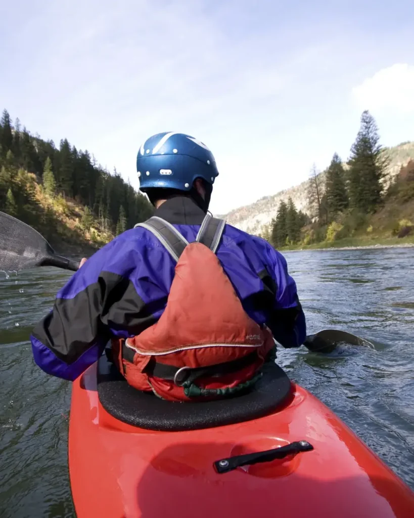 Person in red kayak and blue helmet in Jackson Hole.