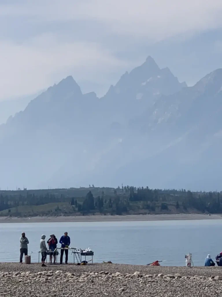 Kayakers camping on the shore of Jackson Lake beneath the Tetons