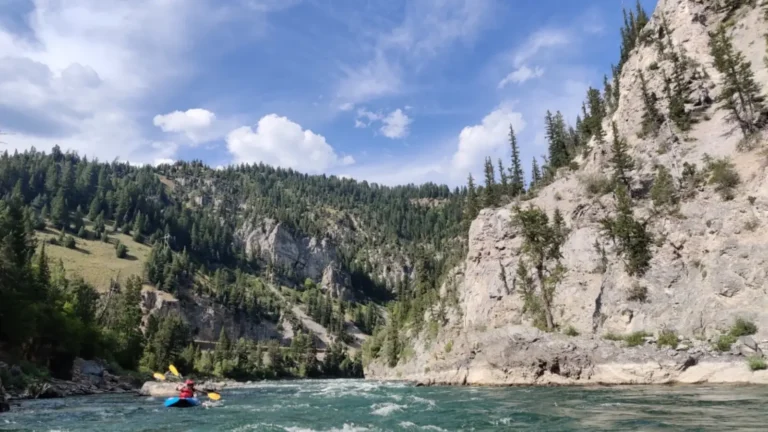 Person in red kayak and calm river water in Snake River.