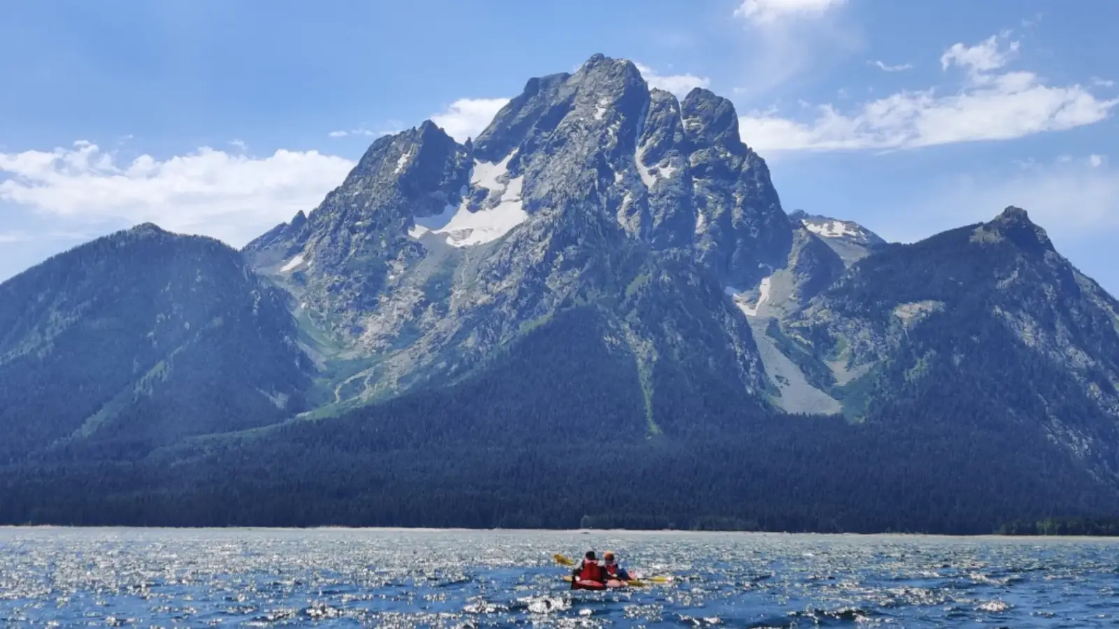 Single person in yellow kayak and calm river or lake water in Yellowstone National Park.