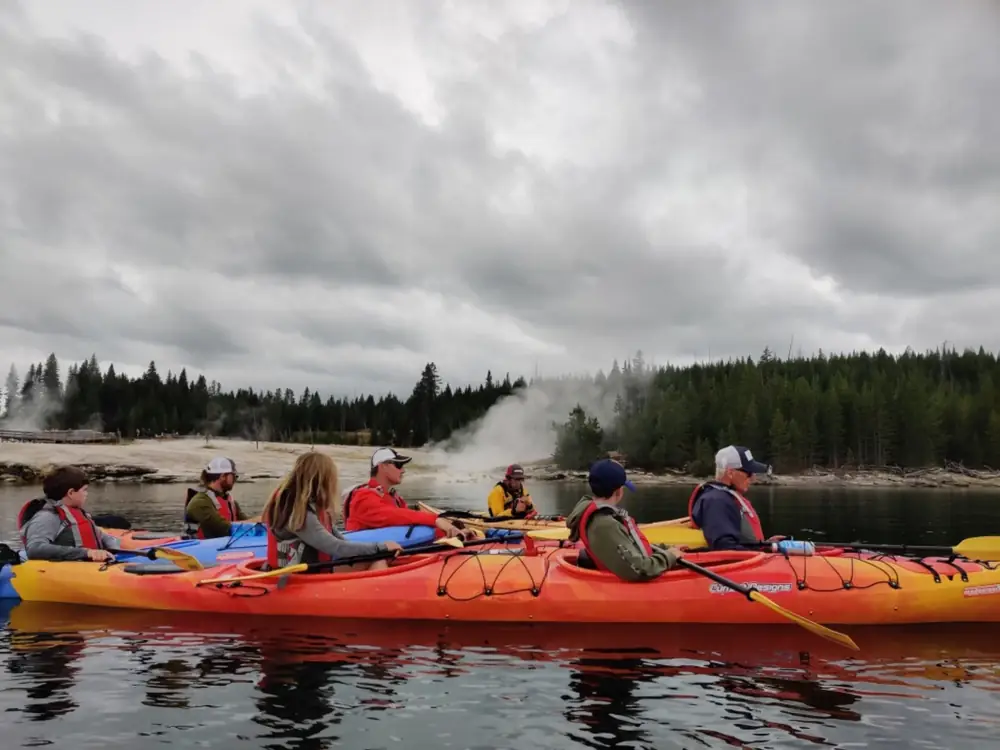 Person in yellow kayak and calm river water in Yellowstone National Park.