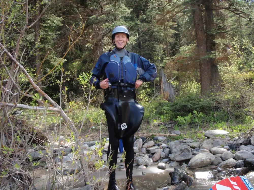 One person standing in a shallow creek and person wearing a helmet in Jackson Hole.