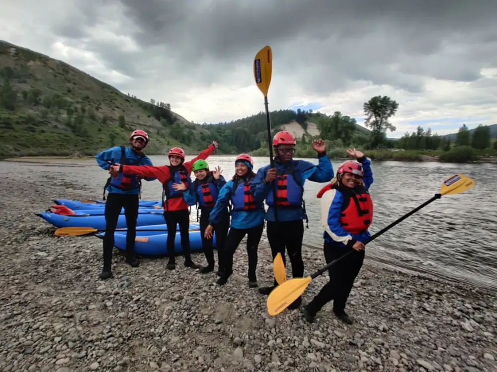 Person in green kayak on water and calm body of water in Snake River.