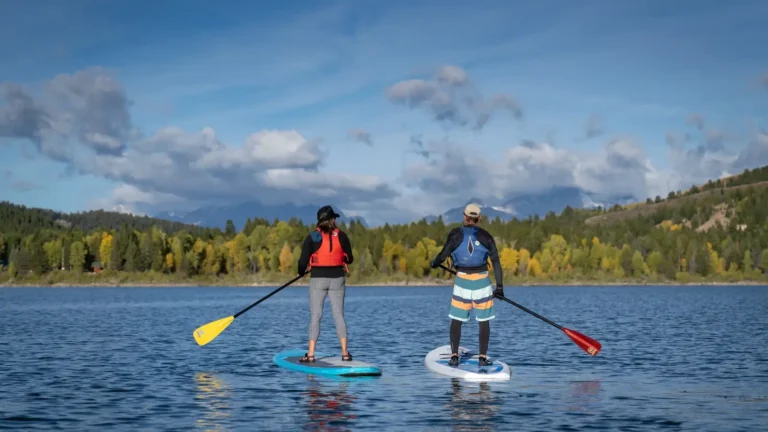 Two people standing on stand-up paddleboards and each person holding a paddle in Jackson Hole.