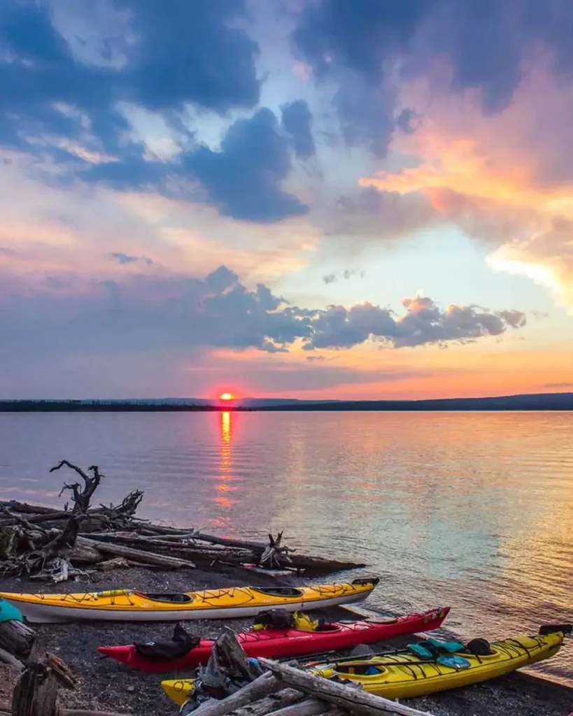 Three kayaks on shoreline and yellow kayak in Snake River.
