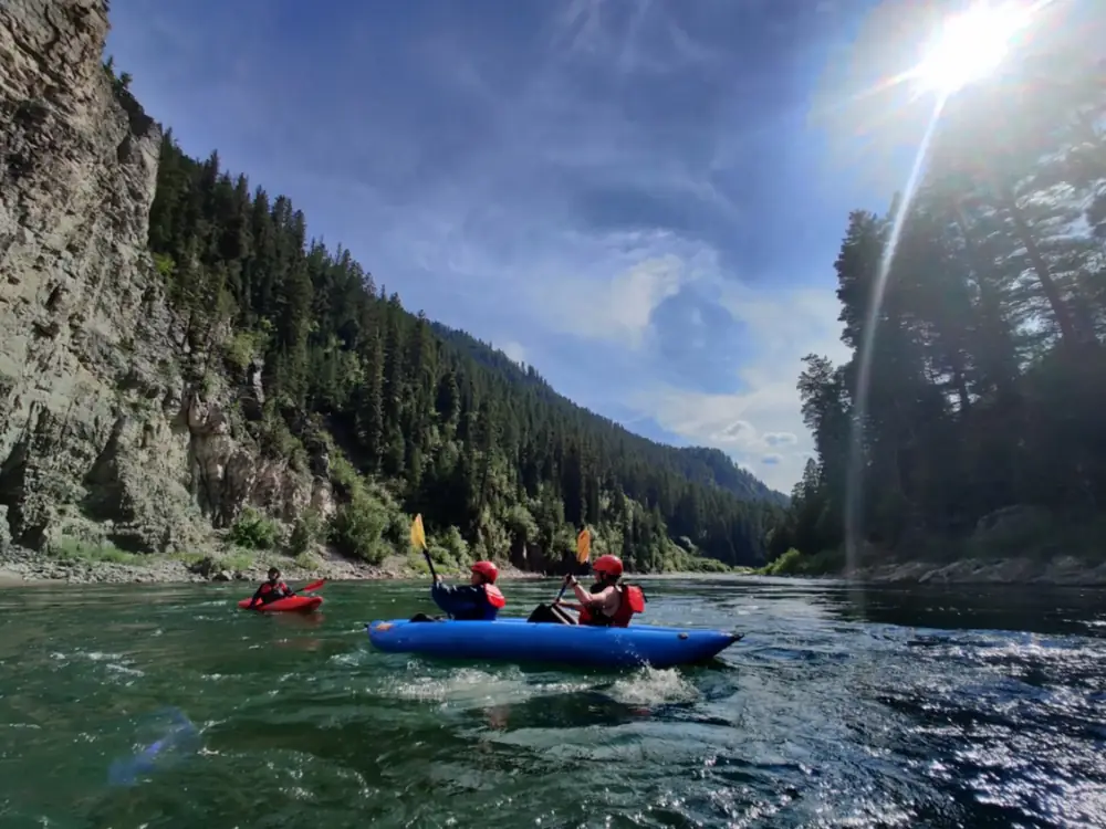 Person in yellow kayak and river with white water rapids in Snake River.