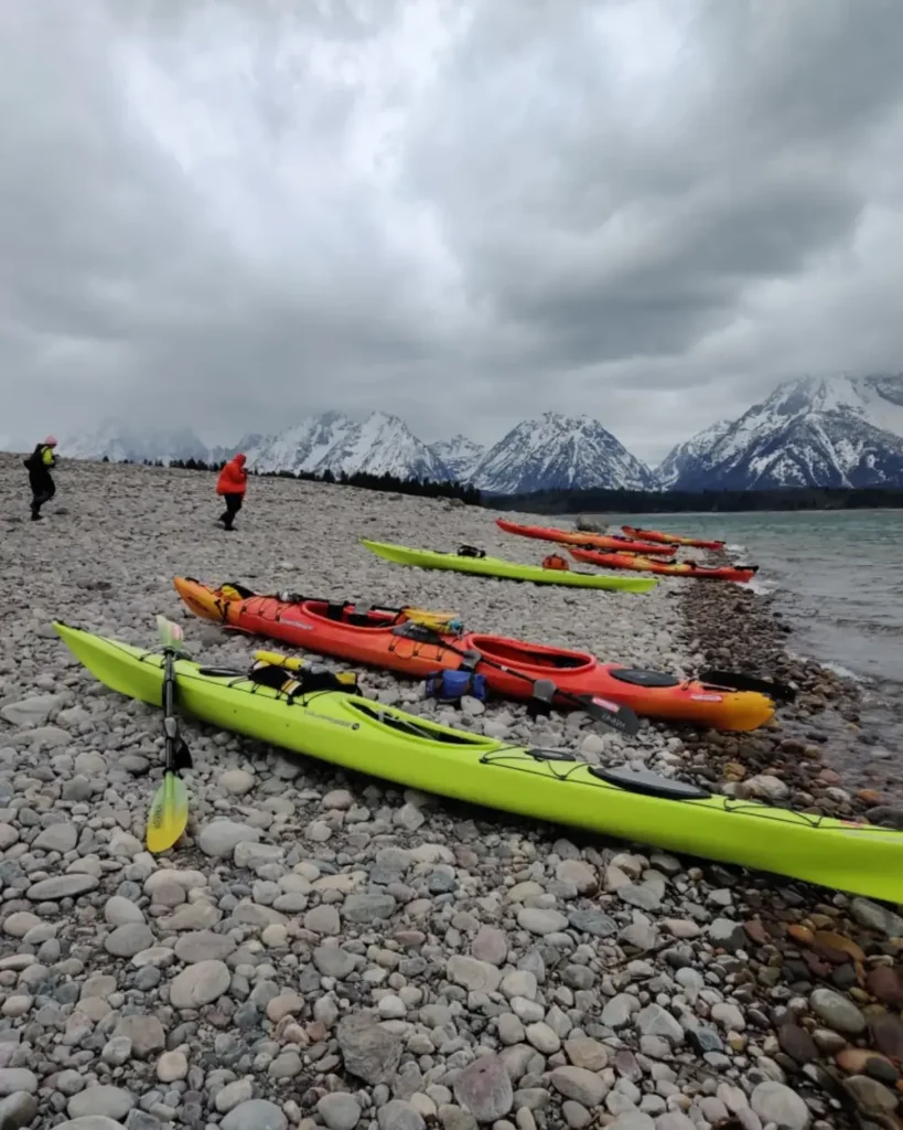 Four kayaks on rocky beach and two red kayaks in Jackson Hole.
