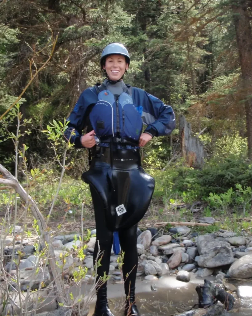 One person standing in a shallow creek and person wearing a helmet in Jackson Hole.