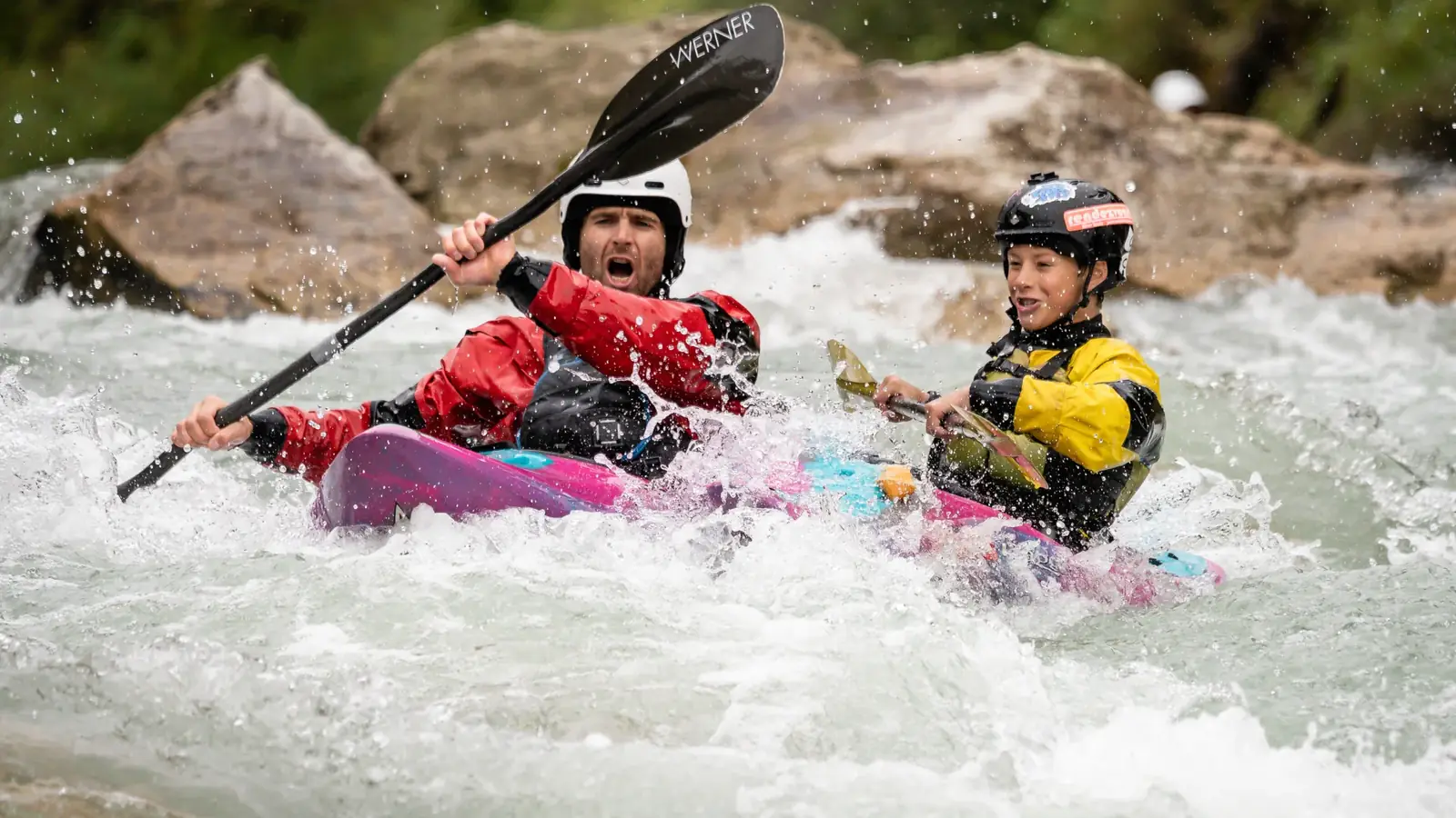 Two people in a tandem kayak and both wearing helmets in Jackson Hole.
