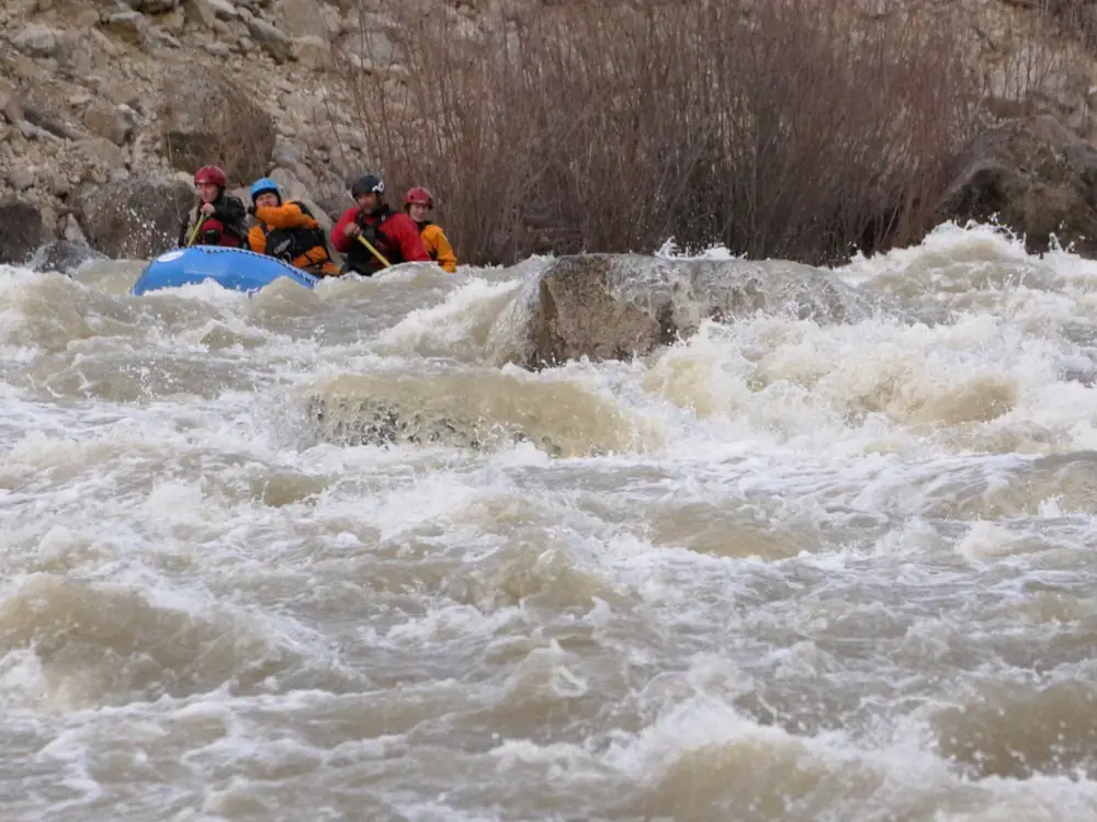 Blue inflatable raft and four people in the raft in Snake River.