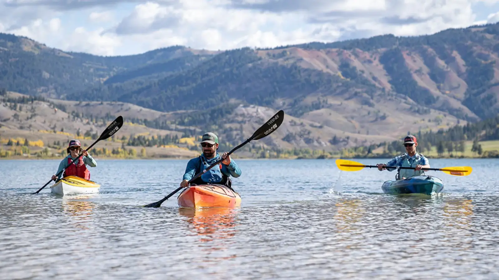 Single person in red kayak and calm lake with reflections in Slide Lake.