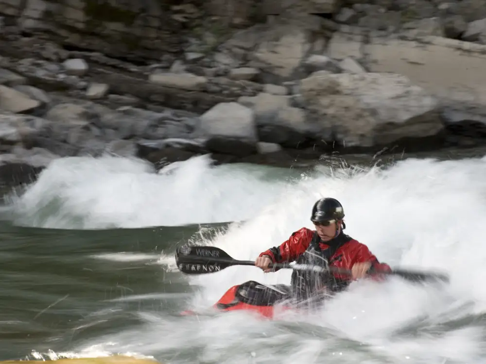 Person in red kayak and river with white water rapids in Jackson Hole.