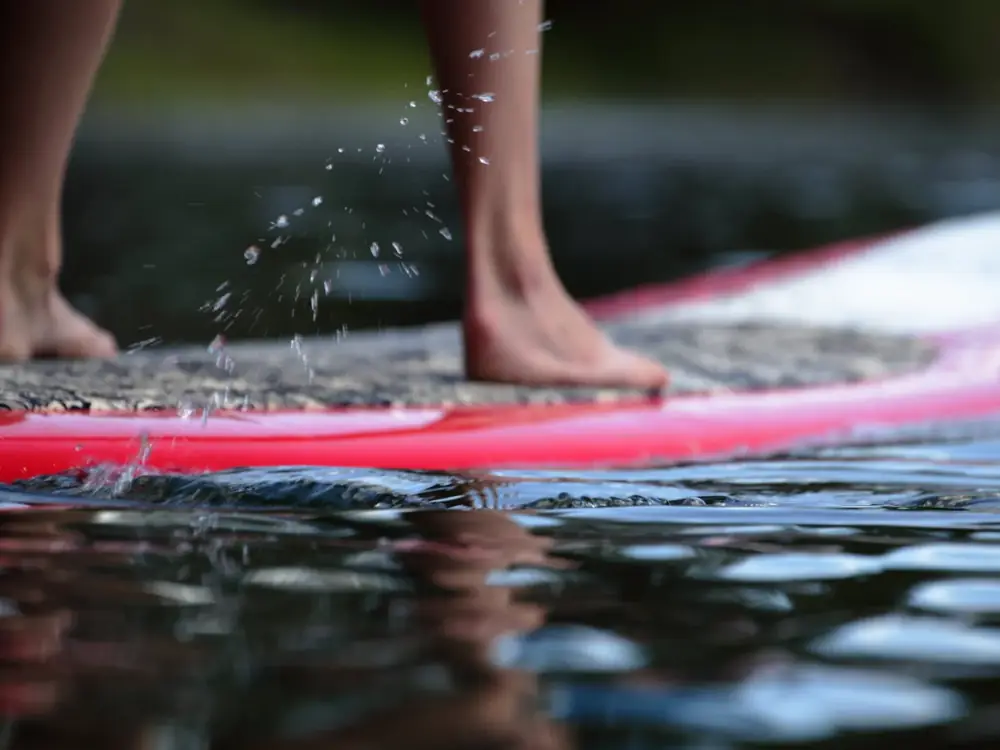 Bare feet and lower legs and red board with textured deck pad in Jackson Hole.