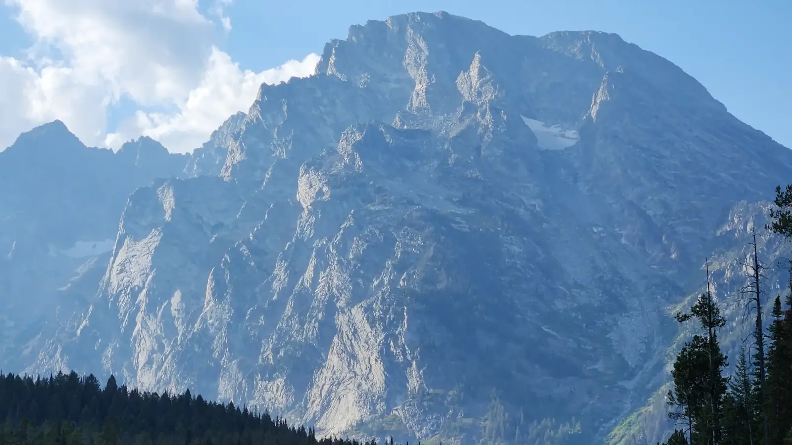 Large rocky mountain with jagged ridges and patches of light-colored rock faces in Yellowstone National Park.