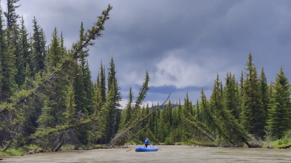One person in blue inflatable raft on river in Yellowstone National Park.