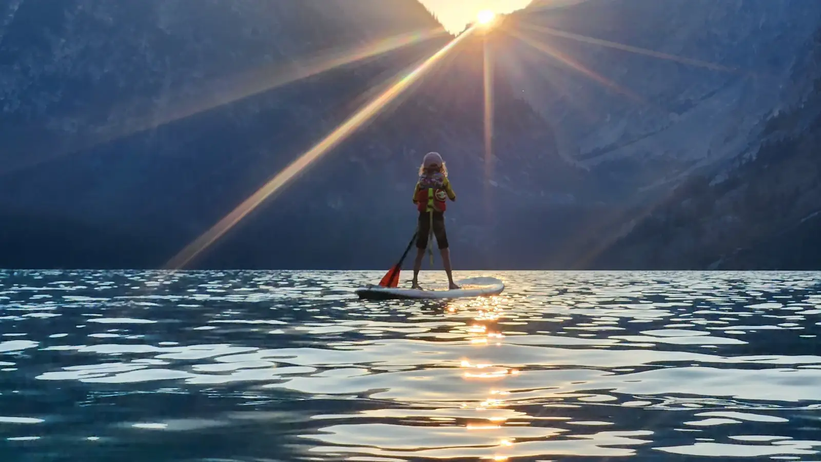 One person standing on a stand-up paddleboard and person facing away from camera in Slide Lake.