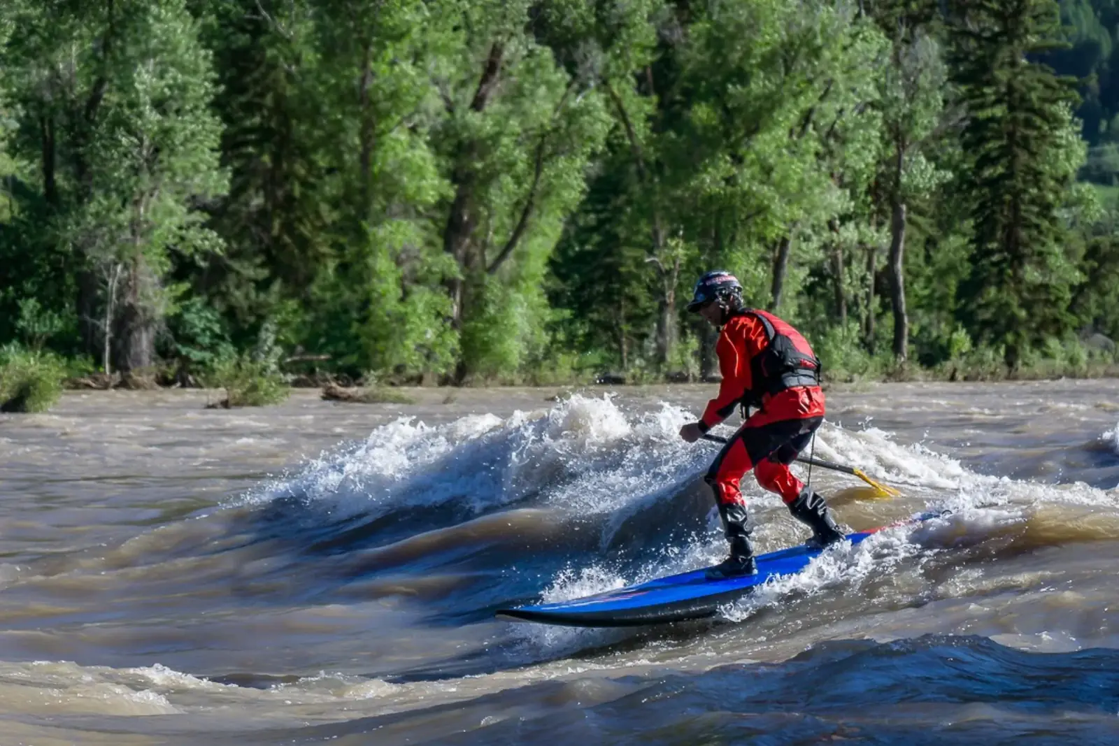 One person standing on a blue board and yellow paddle in the person’s hands in Jackson Hole.