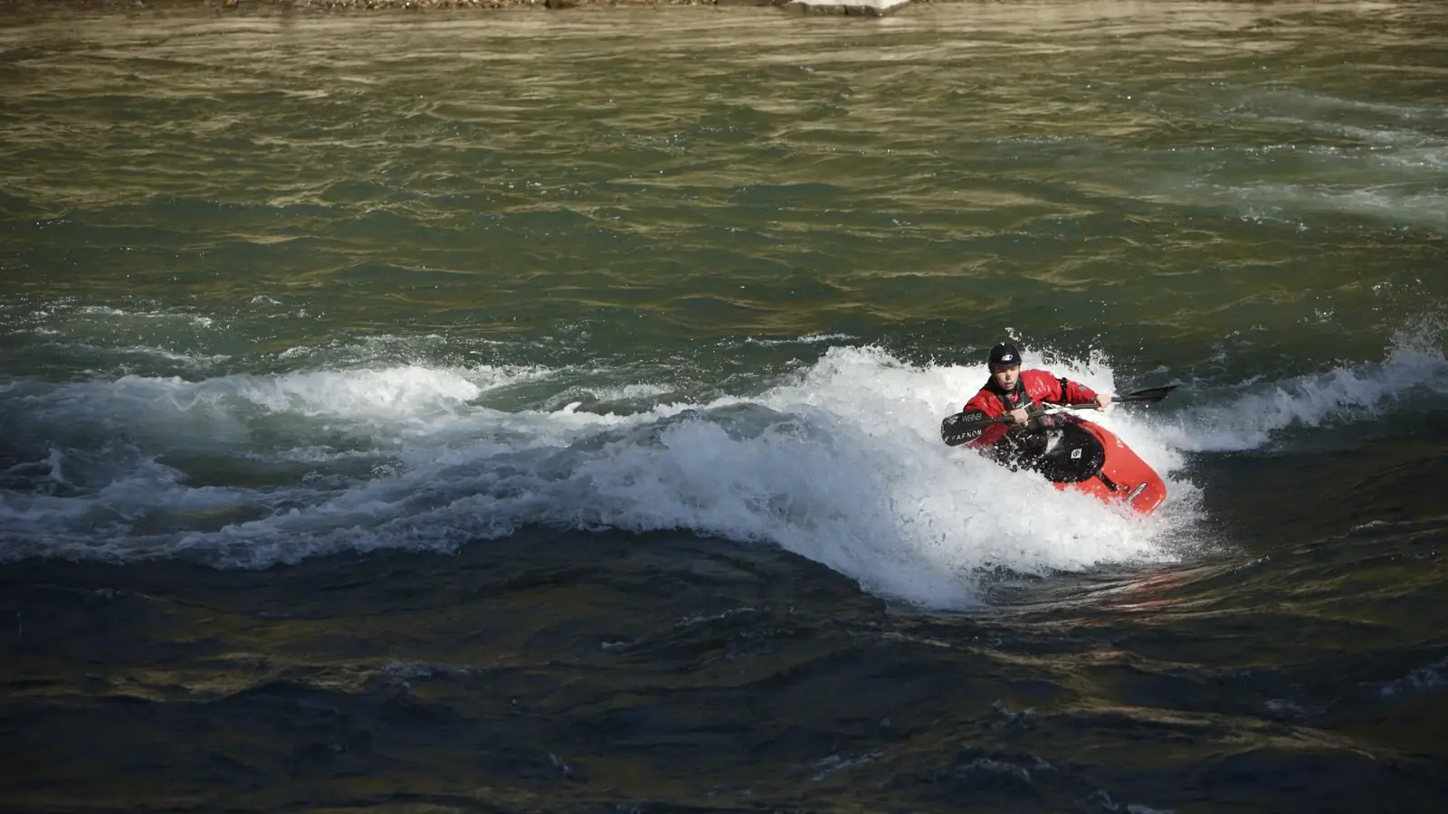 One person in a red kayak and double-bladed paddle in Jackson Hole.