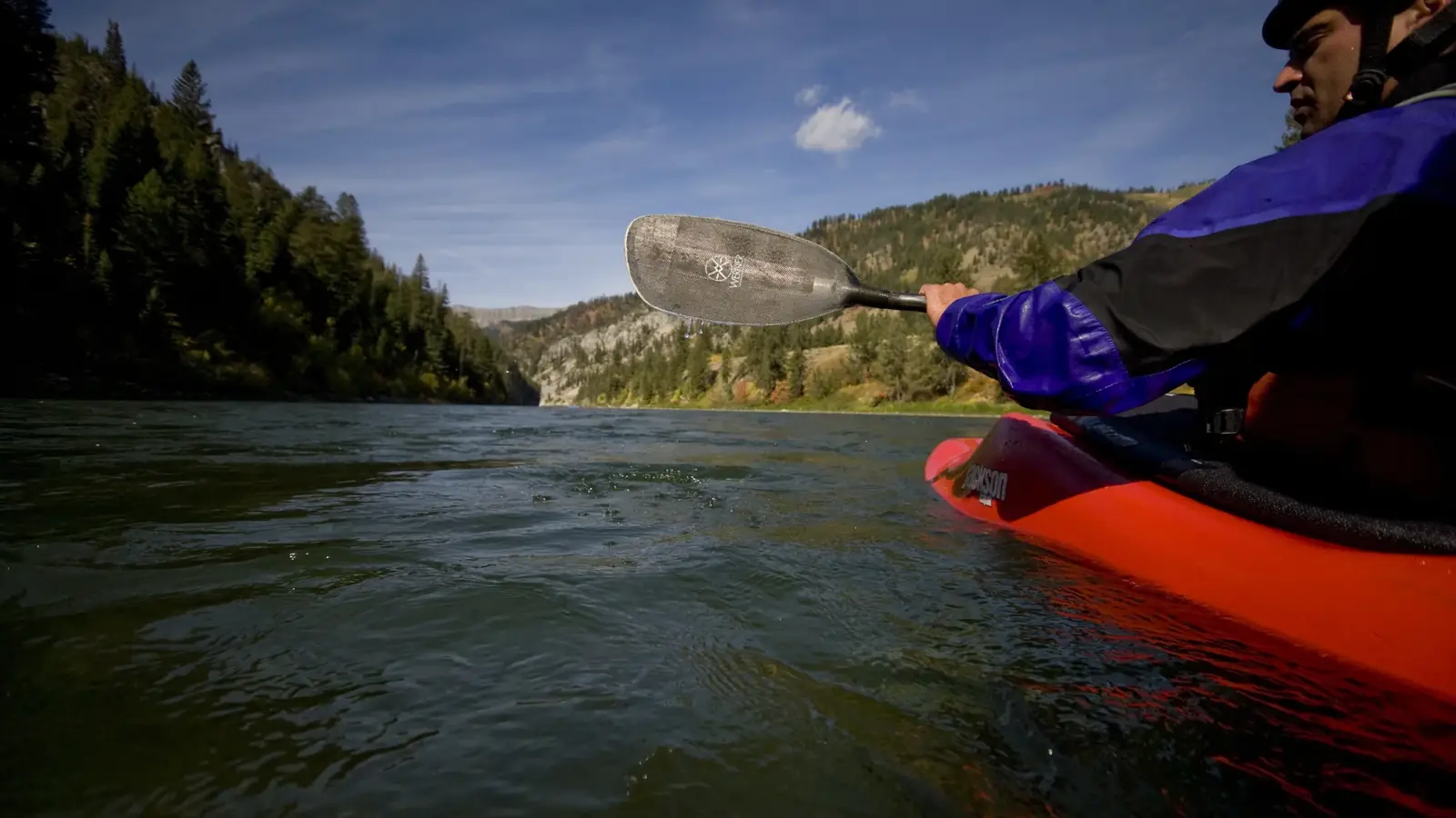 One person in a red kayak and blue helmet in Jackson Hole.