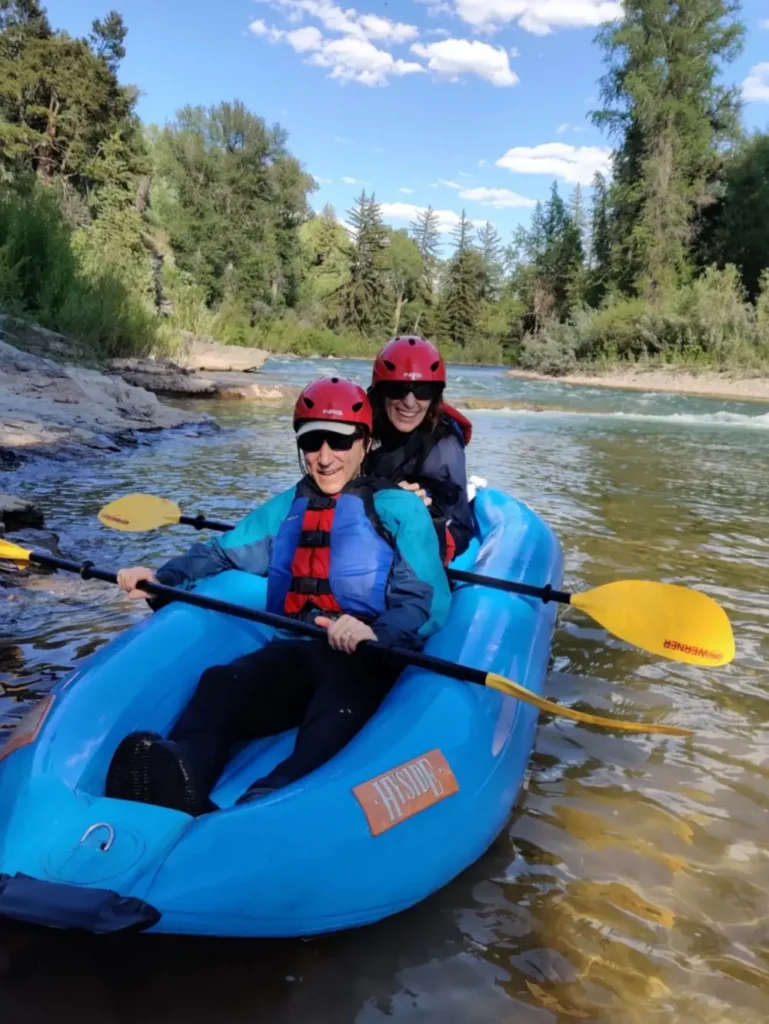 Person in yellow kayak and calm river water in Yellowstone National Park.