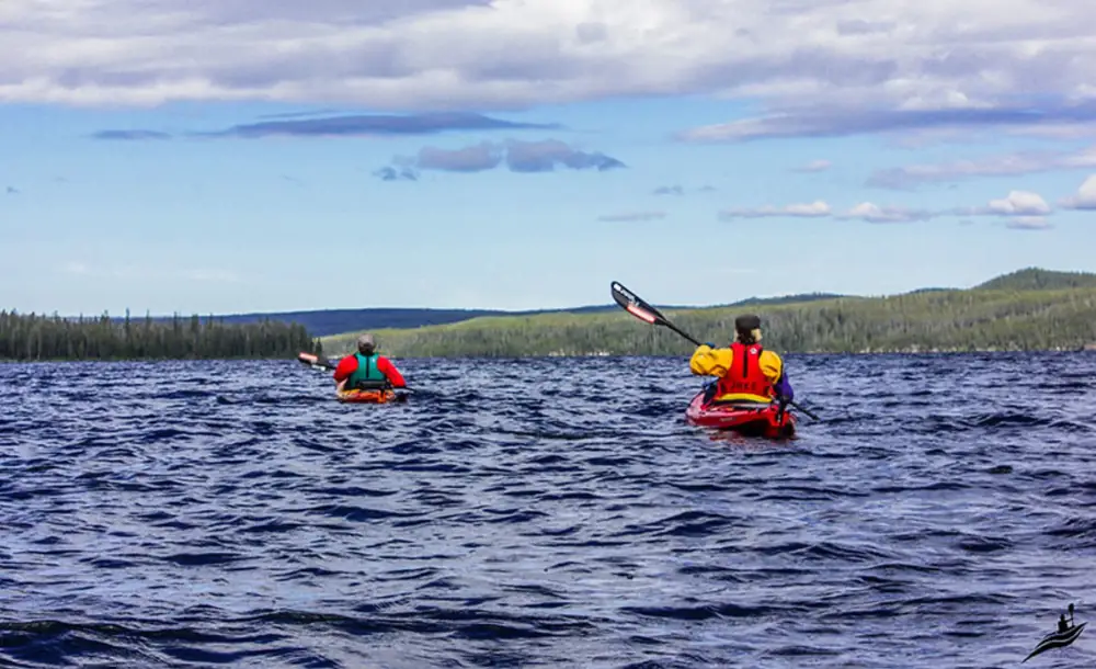 Single kayaker in yellow kayak and wide river with calm water in Yellowstone National Park.