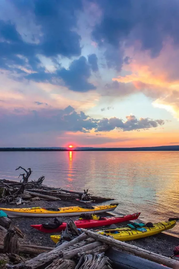 Three kayaks on shoreline and yellow kayak in Yellowstone National Park.