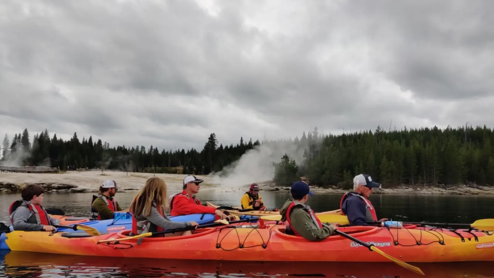 Person in yellow kayak and calm river water in Yellowstone National Park.