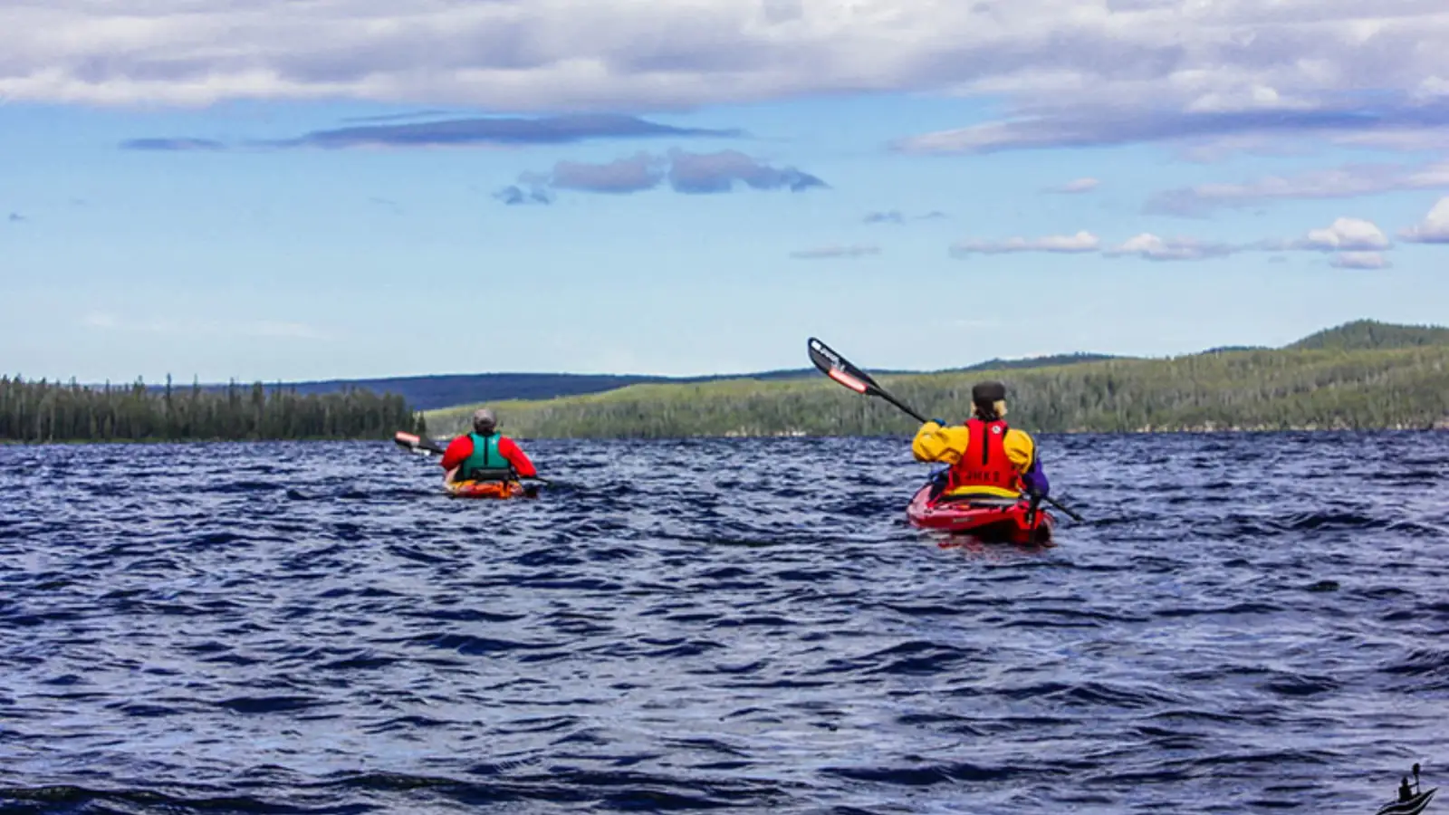 Single kayaker in yellow kayak and wide river with calm water in Yellowstone National Park.