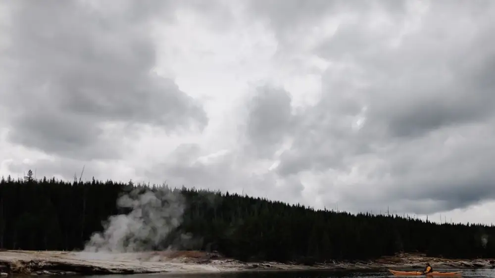 Person in red kayak and calm water surface in Yellowstone National Park.
