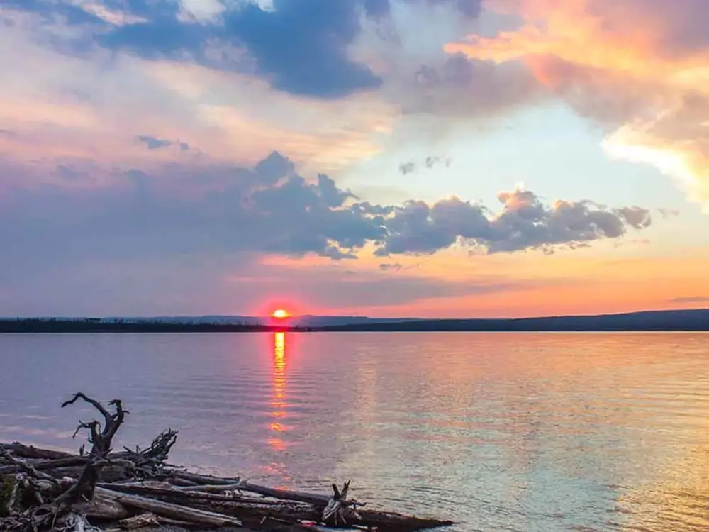 Three kayaks on shoreline and yellow kayak in Yellowstone National Park.